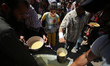 Displaced Palestinians are receiving cooked food rations at a donation point in Deir al-Ba...