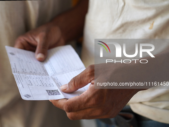 A man is waiting in line with his voting slip to cast his vote inside a polling station during the first phase of the general elections in K...