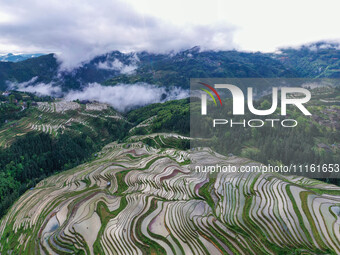 An aerial photo is showing clouds shrouding the terraced fields of Kampung deep in the mountains in Congjiang County, Qiandongnan Miao and D...