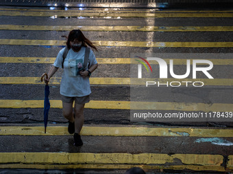 A woman is holding an umbrella while crossing the road in Hong Kong, on April 26, 2025. (