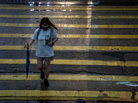 A woman is holding an umbrella while crossing the road in Hong Kong, on April 26, 2025. (