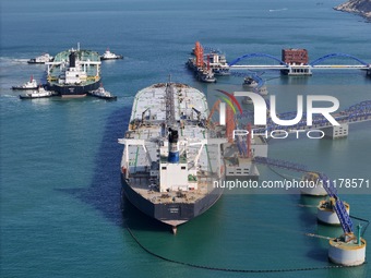 A very large oil tanker is being assisted by a tugboat as it berths at Yantai Port's 300,000-ton crude oil terminal in Yantai, Shandong Prov...