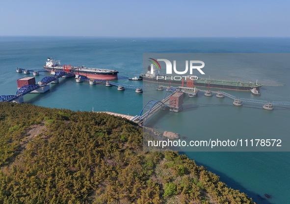 A very large oil tanker is being assisted by a tugboat as it berths at Yantai Port's 300,000-ton crude oil terminal in Yantai, Shandong Prov...
