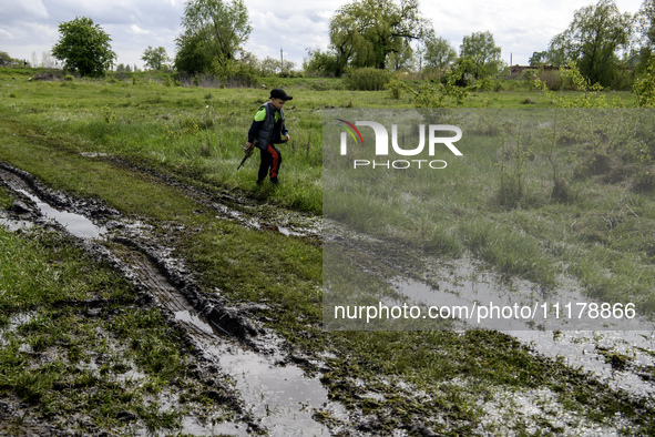 A boy is walking through puddles with a toy machine gun after rain on the road in a village in the Kyiv region, Ukraine, on April 25, 2024. 