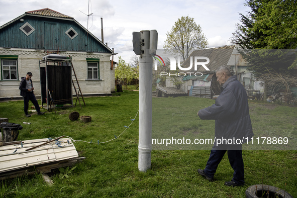 Mykola Kravchenko (R) is displaying a part of a Russian Uragan rocket that fell near his house in the village in the spring of 2022, which h...
