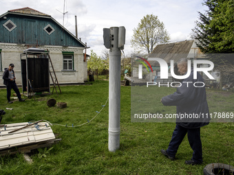 Mykola Kravchenko (R) is displaying a part of a Russian Uragan rocket that fell near his house in the village in the spring of 2022, which h...