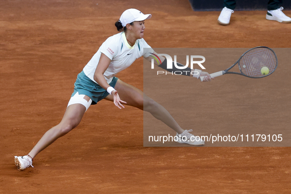 Xiyu Wang of China is in action against Iga Swiatek of Poland on Day Three during their second-round match at the Mutua Madrid Open at La Ca...