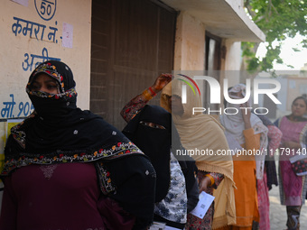 Women are standing in a queue at a polling station to vote during the second phase of the Indian General Elections in Vrindavan district, Ut...
