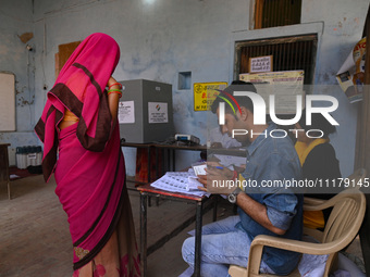 An election official is checking the document of a woman who is coming to cast her vote during the second phase of the Indian General Electi...