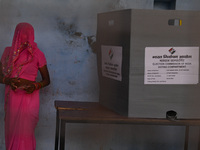 A woman is standing beside the voting compartment after casting her vote in an Electronic Voting Machine (EVM) at a polling station during t...