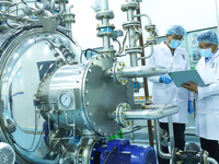 Technicians are checking the content of plant active ingredients on a computer at an automated production line for supercritical fluid extra...