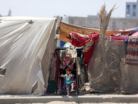Displaced Palestinians are sitting outside to escape the searing heat in their camp tents in Deir El-Balah, in the central Gaza Strip, on Ap...