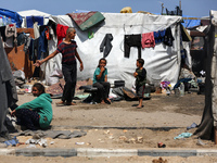 Displaced Palestinians are sitting outside to escape the searing heat in their camp tents in Deir El-Balah, in the central Gaza Strip, on Ap...