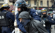 A demonstrator is being arrested by CRS riot police while another is being helped by a com...
