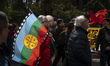 An elderly person is holding a Mapuche flag while marching for International Workers' Day...