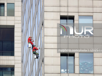 Workers are cleaning the windows on each floor of a high-rise building in the Chaoyang district of Beijing, China, on May 1, 2024. In Beijin...