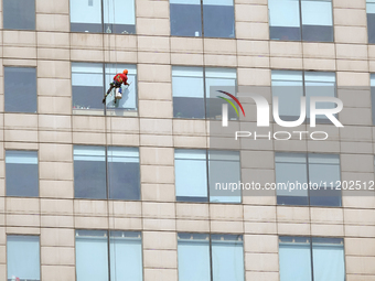 Workers are cleaning the windows on each floor of a high-rise building in the Chaoyang district of Beijing, China, on May 1, 2024. In Beijin...