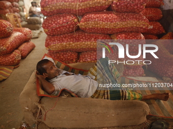 A vendor is sleeping on a hot summer day at a market in Dhaka, Bangladesh, on May 2, 2024. (