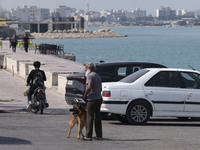 An Iranian man and his dog are standing on a coastal street in Bushehr, Iran, the country's first nuclear seaport city, located on the north...