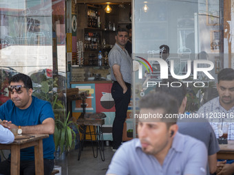 Iranian men are sitting at an outdoor cafe in Iran's first nuclear seaport city of Bushehr, located in Bushehr province on the northern coas...