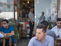 Iranian men are sitting at an outdoor cafe in Iran's first nuclear seaport city of Bushehr, located in Bushehr province on the northern coas...