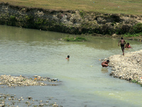 Children are jumping as they bathe to cool off and beat the heat in the waters of the Balason River in Siliguri, India, on May 3, 2024. (