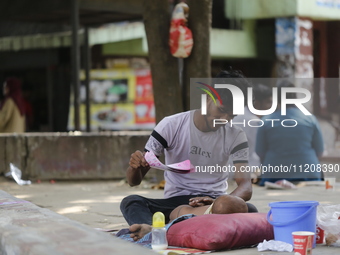 A man is cooling his child with papers on a hot summer day in Dhaka, Bangladesh, on May 4, 2024. (