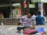A man is cooling his child with papers on a hot summer day in Dhaka, Bangladesh, on May 4, 2024. (