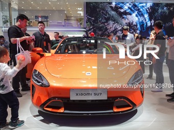Visitors are looking at the Xiaomi Auto SU7 electric car at the 2024 Beijing International Automotive Exhibition in Beijing, China, on May 3...