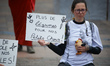 A young woman is holding a placard that reads 'No more vegetables for our kids' as Extinct...