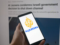 The Al Jazeera logo is being displayed on a smartphone with the Al Jazeera website visible in the background in this photo illustration in B...