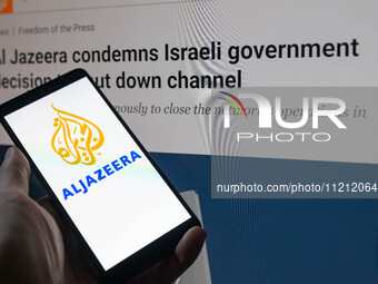 The Al Jazeera logo is being displayed on a smartphone with the Al Jazeera website visible in the background in this photo illustration in B...