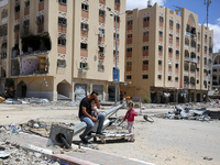 Palestinians are sitting amid the ruins of destroyed residential buildings in Qatari-funded Hamad City, following an Israeli raid, amid the...