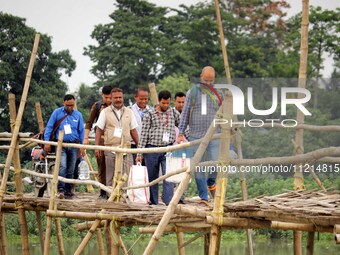 Election officials are carrying EVMs and other materials to their respective polling booths over a bamboo bridge on the eve of the third pha...