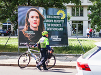 A police officer is standing next to an election campaign poster of the German Green Party candidate Terry Reintke, which reads: ''A strong...