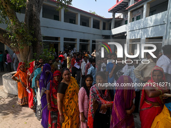 People are waiting in a queue to cast their votes at a polling station during the third phase of the Indian General Elections in Hathras dis...