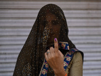 A woman is showing her inked finger after casting her vote at a polling station during the third phase of the Indian General Elections in Ha...