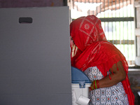 A woman is casting her vote in the Electronic Voting Machine (EVM) at a polling station during the third phase of the Indian General Electio...