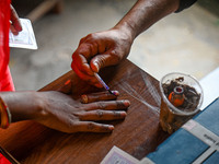 An election official is putting ink on the finger of a woman who is casting her vote at a polling station during the third phase of the Indi...