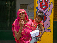 An elderly woman is showing her inked finger after casting her vote at a polling station during the third phase of the Indian General Electi...