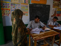 Election officials are checking the documents of a woman at a polling station during the third phase of the Indian General Elections in Hath...