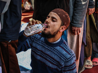 A Muslim boy is drinking water as he sits on the ground while others are donating blood during a blood donation camp in Sopore District, Bar...