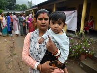 A woman is showing her ink-marked finger after casting her ballot at a polling station during the third phase of voting in India's general e...
