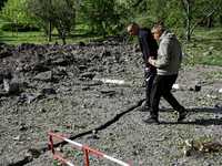 Two men are approaching a crater in Zaporizhzhia, Ukraine, on May 8, 2024, after a massive Russian missile and drone attack occurred during...