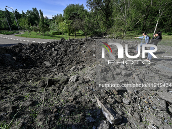 Two women are standing by a crater after a massive Russian missile and drone attack at night in Zaporizhzhia, southeastern Ukraine, on May 8...