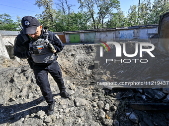 A police officer is standing by a crater at a garage cooperative after a massive Russian missile and drone attack during the night in Zapori...