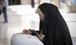 A veiled Iranian voter is casting her first electronic ballot into an electronic ballot bo...