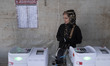 An Iranian woman is standing behind electronic ballot boxes at a polling station during th...