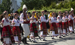 People wearing traditional folk costumes are performing Bulgarian folk dances in the cente...