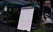 Protesters are seen at a makeshift camp, displaying a list of demands at the University of...